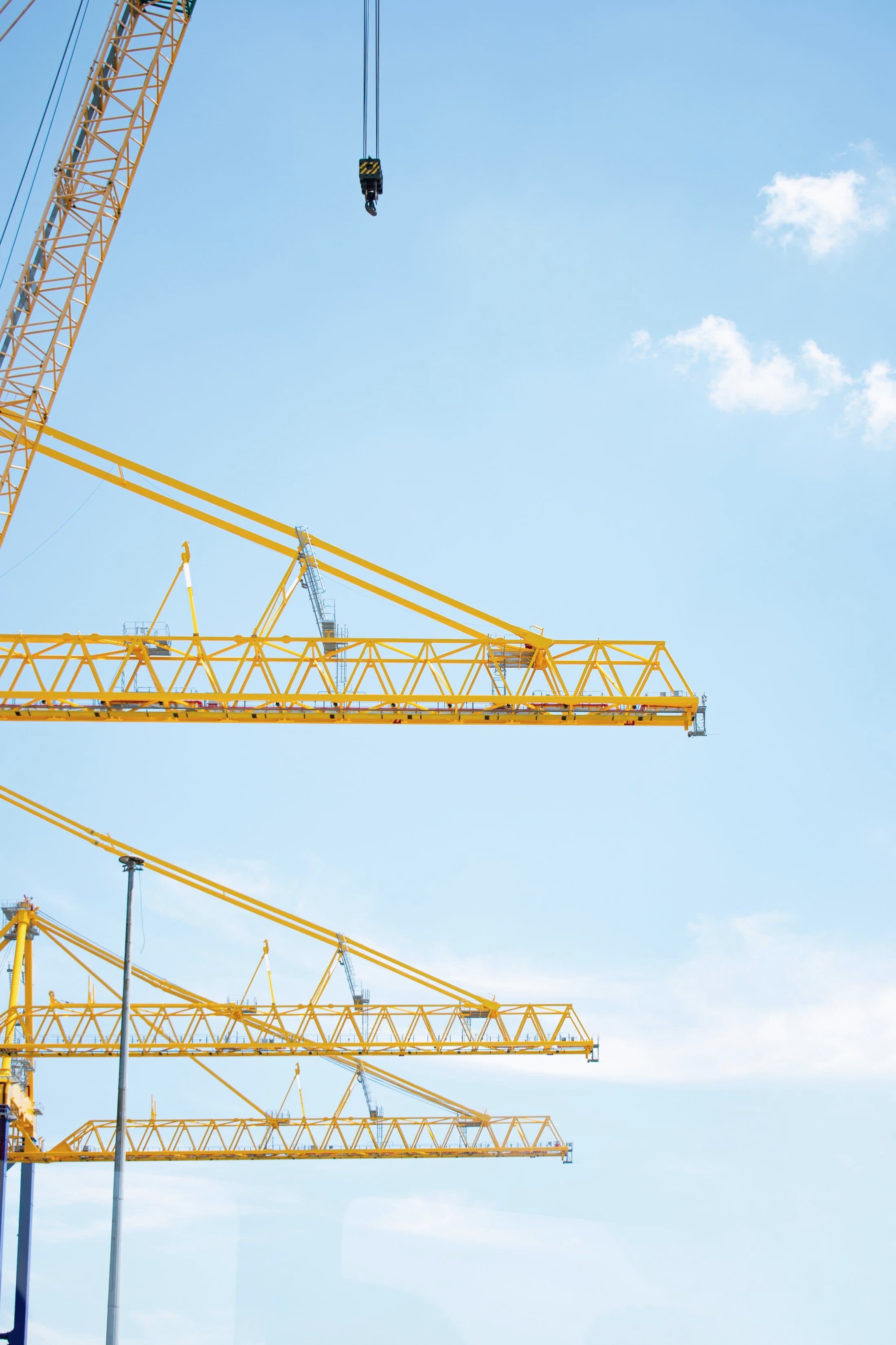 Yellow tower cranes against a clear blue sky on a construction site