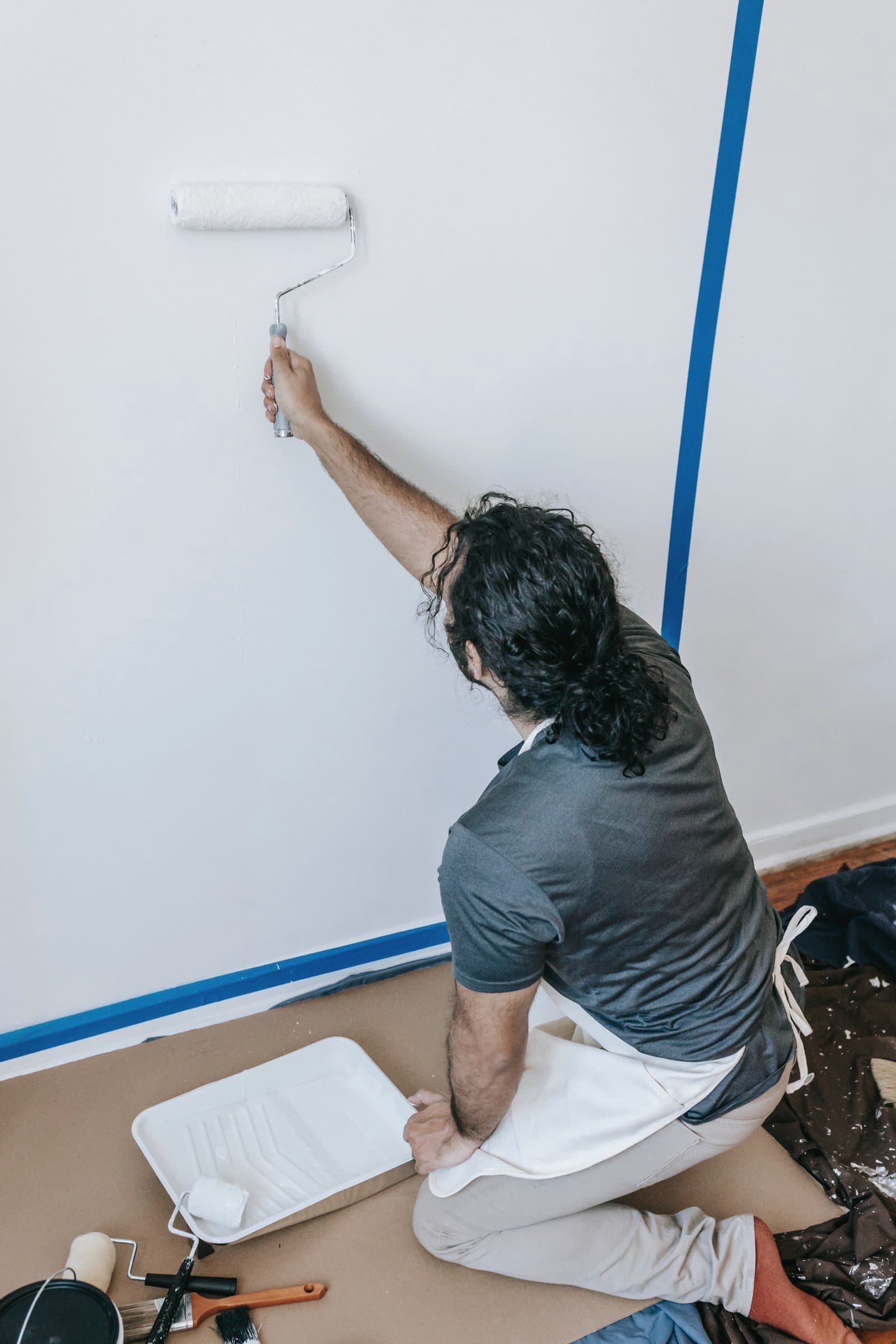 Painter applying white paint to an interior wall with a roller