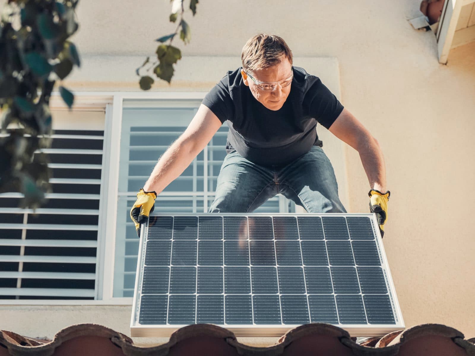 Technician installing a solar panel on a house roof