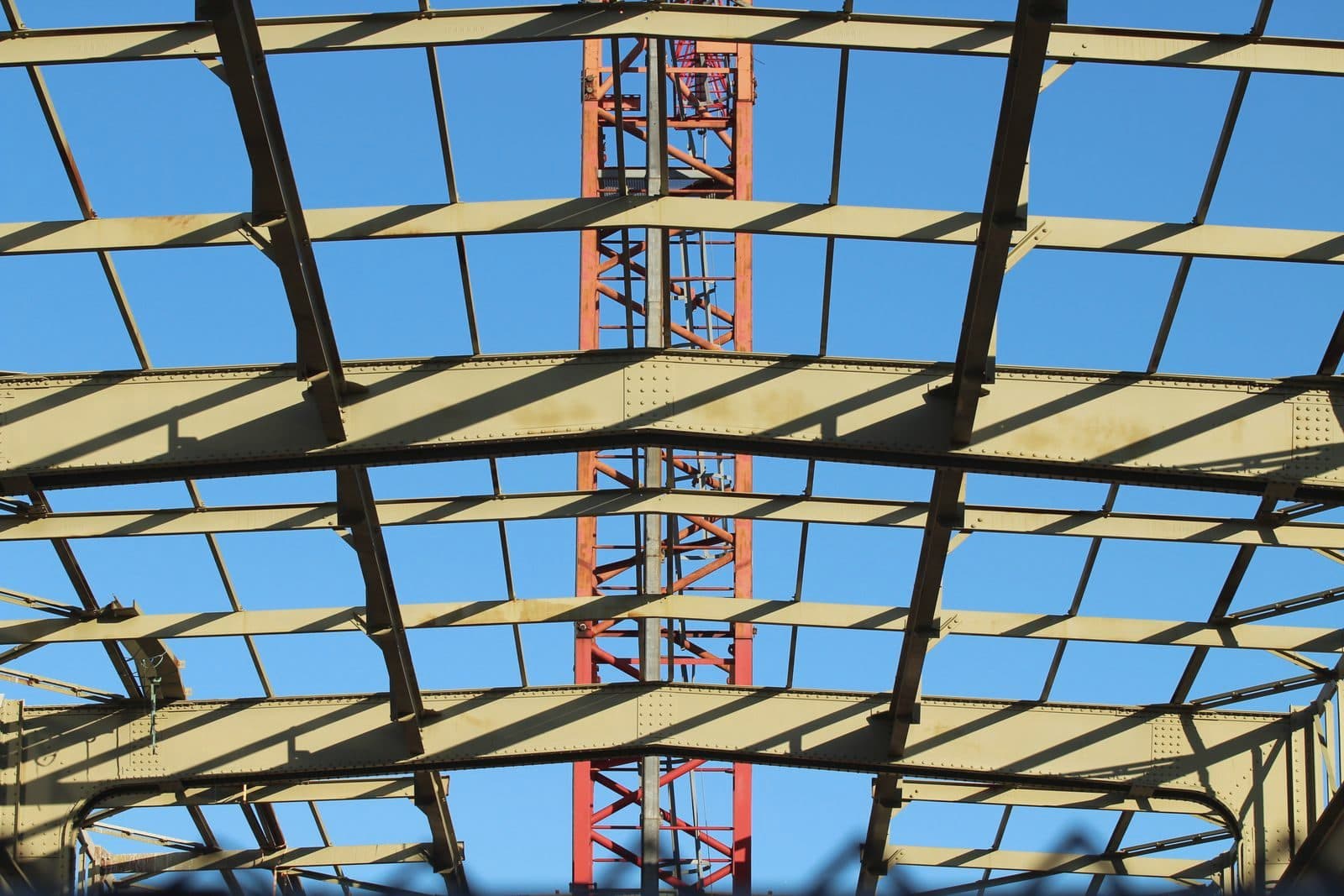 Structural steel roof frame under construction against blue sky